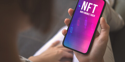 Banner non-fungible token. Smartphone screen with NFT logo in woman hand. Concept of crypto art and technology