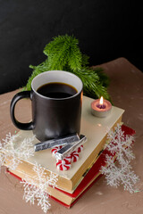 a New Year's card a cup of coffee on the books next to a candle chocolates Christmas candies snowflakes and fir twigs