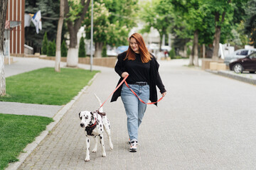View of young Caucasian female cynologist walking at city urbanity during morning time for training...