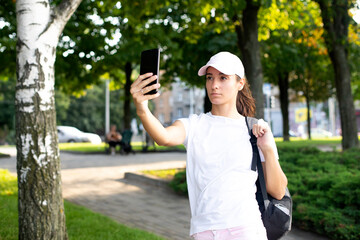 Model girl in  a white T-shirt and a cap communicates on the phone. Video calls.