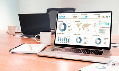 Mock up sales summary slide show presentation on display laptop with notebook and coffee cup on table in meeting room