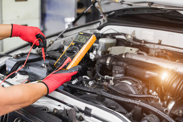 A technician is checking the car battery for availability.