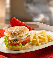 hamburguesa de queso y patatas fritas sobre bandeja . cheeseburger and french fries on tray.