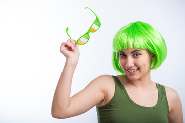 Cheerful young woman in green wig and funny glasses celebrating st patrick's day on a white background