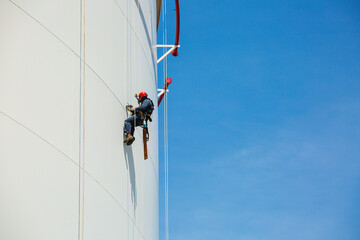 Male workers control rope down height tank rope access inspection of thickness shell plate storage tank.