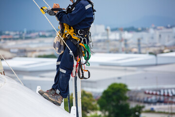 Close-up male workers control equipment rope down top roof tank rope access inspection of thickness shell plate storage tank gas © chitsanupong