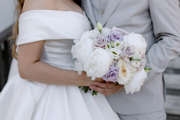 Wedding bouquet of beautiful flowers In young female hands of the bride Elegant white dress for the wedding ceremony Newlyweds holiday