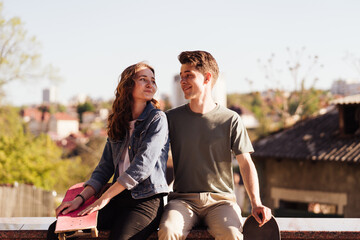 Caucasian skateboarder couple standing together prepare themselves to surf skate in the city Handsome man and beautiful woman enjoy skateboard exercising.