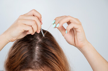 Caucasian woman finds gray hair and removes it with tweezers. Signs of aging.