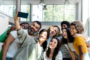 Group of multiracial coworker friends take a selfie in the office during work break. Copy space. - Powered by Adobe