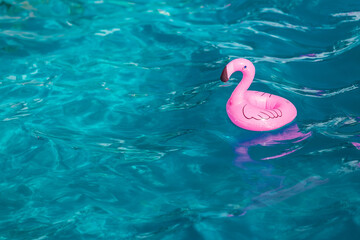 Small pink air flamingo balloon floating in a blue party pool