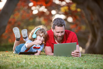 father and son use modern communication technology in park. family blog.