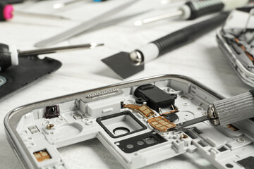 Damaged smartphone and repair tool on table, closeup