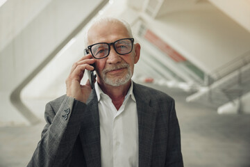 Business man with gray hair speaks by smartphone. Modern business old man.