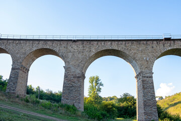 Viaduct in the mountains. Stone railway bridge between the hills.