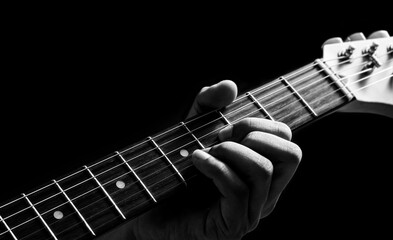 close up male musician left hand playing chord on electric guitar neck. music background - obrazy, fototapety, plakaty