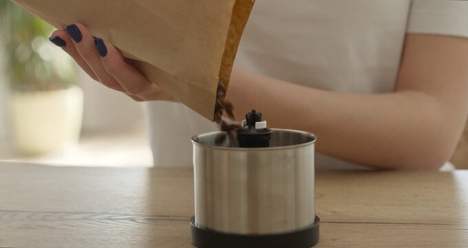 Woman putting coffee beans in grinder