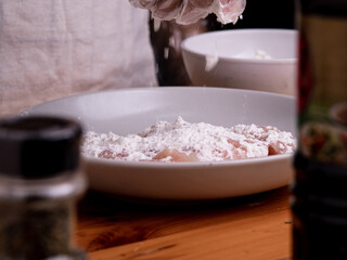 Hand of a woman wearing gloves is marinating chicken pieces in a bowl with soy sauce and flour to make delicious fried chicken at home. Cooking concept.