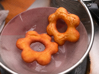 Frying tasty and homemade donuts on hot oil in a pan on the kitchen stove. cooking process.