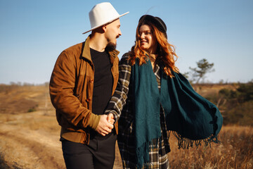 Lovely hipster couple enjoying each other in the autumn park. Nice autumn day. Young couple walking and hugging outdoors, The concept of youth, love and lifestyle.