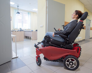 Caucasian woman in electric wheelchair in university corridor.