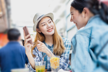 Traveler Asian woman friend travel in Bangkok, Thailand, sweet couple taking photo . Lifestyle couple travel in city concept.Young fun happy Asian tourist backpacker travel eating street food.