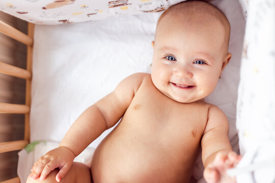 Adorable happy smilling four months old naked baby at home. Beautiful conceptual image of Maternity.