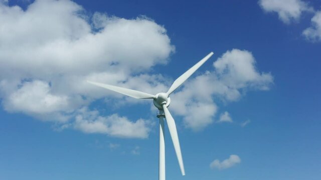 a plain wind turbine turning in front of a blue sky with movement