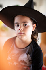 Vertical portrait of caucasian little girl dressed as a witch for Halloween party.
