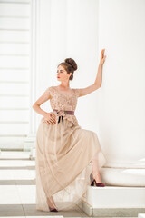 Young woman in a luxurious beige dress posing on the street