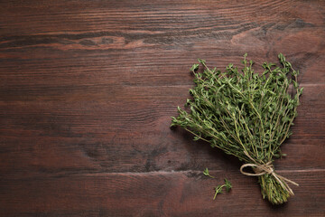 Bunch of aromatic thyme on wooden table, top view. Space for text