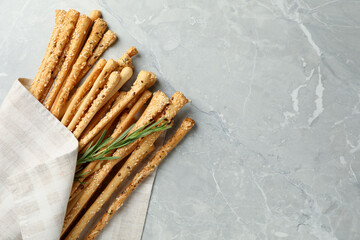 Delicious grissini sticks and rosemary on grey marble table, flat lay. Space for text
