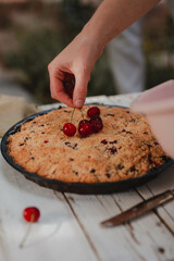 hand putting berries on a cake 