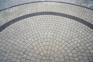 Paving stone laid in a semicircle. Well visible pattern of stones. Top view of the square from the old pavers