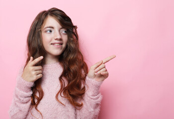 Obraz premium Little child girl with long hair pointing back on empty copy space for advertisement text of new toys store