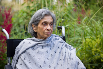 Old Indian woman in a wheelchair. UK elderly mental health - obrazy, fototapety, plakaty