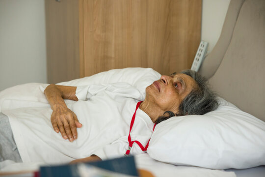 Frail old woman lying in a bed in hospital or nursing home, UK