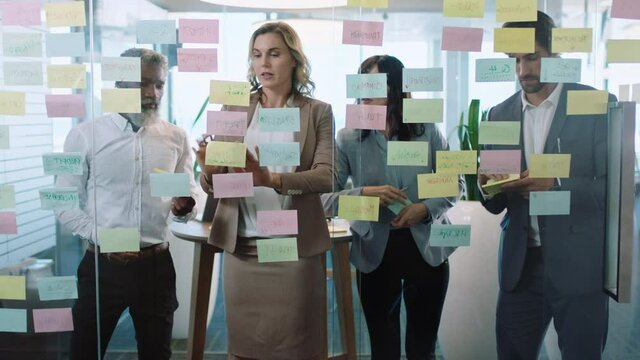 group of business people meeting using sticky notes brainstorming colleagues working on problem solving strategy thinking of solution for project in corporate office 4k