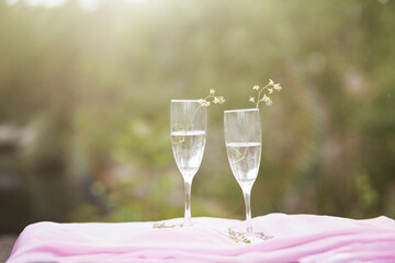 Champagne with wildflowers outside. Photo picnic on the nature with sunlight. Celebrating life and solitude concept. Glasses with champagne
