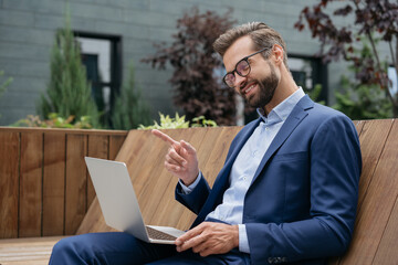 Handsome smiling businessman using laptop computer having video call, talking, explaining something. Happy man influencer communication with subscribers. Online meeting, video conference concept