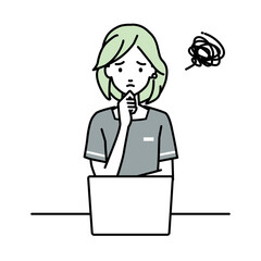 デスクで座ってPCを開いて困っているエステ店員の女性