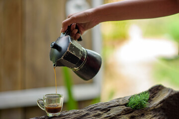 Fototapeta na wymiar hand pouring coffee into a cup
