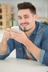 man sat in the kitchen enjoying a hot drink