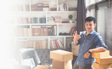 Confident young businessman working at online business store.Small business owner packing in the cardbox at home.