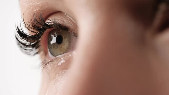 Lachrymation, tears. Close-up view of female human eye with few tears on white background. Slow motion, macro shot