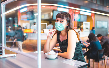 Asian woman sitting separated in restaurant eating food .keep social distance for protect infection from coronavirus covid-19, restaurant and social distancing concept.