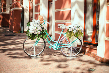 Fototapeta na wymiar Bright blue female model bike with flowers parked near the building on a sunny day