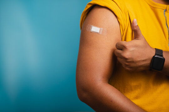 A teenage man shows his sleeve with a bandage after vaccination. medical first aid concept and health care
