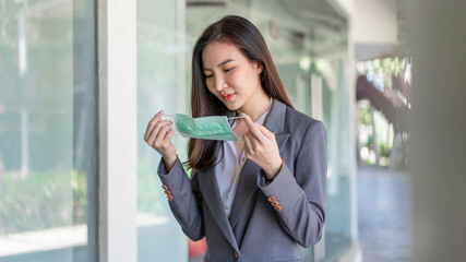 Working woman concept a working woman preparing herself before meeting the client by wearing the disposable face mask to protect herself from the corona virus