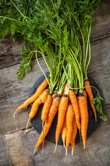 Healthy ripe juicy carrots on a wooden kitchen table. The concept of organic nutrition and autumn harvesting vegetables. Top view flat lay background.